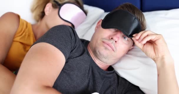 Waking up young man in sleep mask looking surprised at woman 4k movie. Promiscuous sex concept - Footage, Video