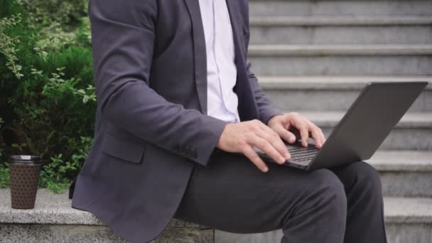 Ein Mann im Anzug beendet online seine Arbeit in der Stadt, während er den Laptop schließt. Beschnitten. Wirtschaft, Kommunikation, Technologiekonzept. Zeitlupe - Filmmaterial, Video
