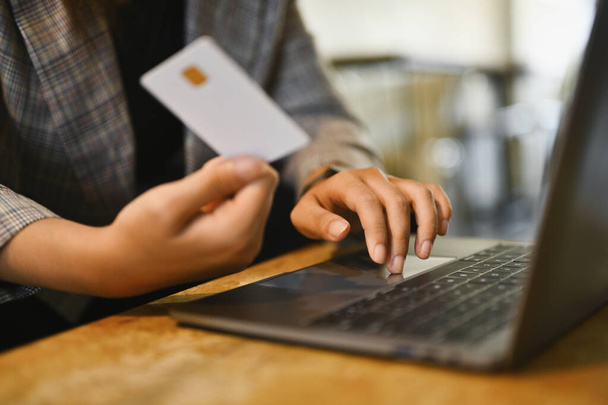 Жінка тримає кредитну картку, оплачуючи рахунок онлайн-платежем через Інтернет на ноутбуці. - Фото, зображення