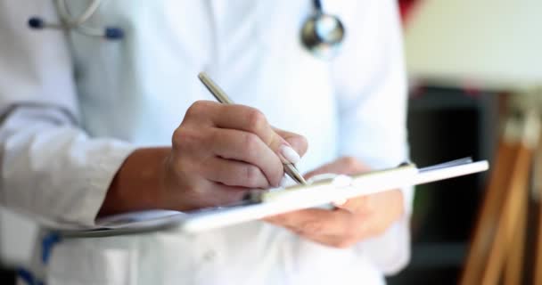 Female doctor nurse practitioner writing patient information. Cardiologist writing prescription in paper notepad and working with medical documents in clinic - Footage, Video