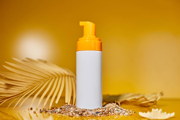 Αντιηλιακό σωλήνα mockup με κοχύλια, άμμο κίτρινο φόντο, καλοκαιρινές διακοπές και spf uv-protecting έννοια φροντίδας του δέρματος, σκληρό φως. - Φωτογραφία, εικόνα
