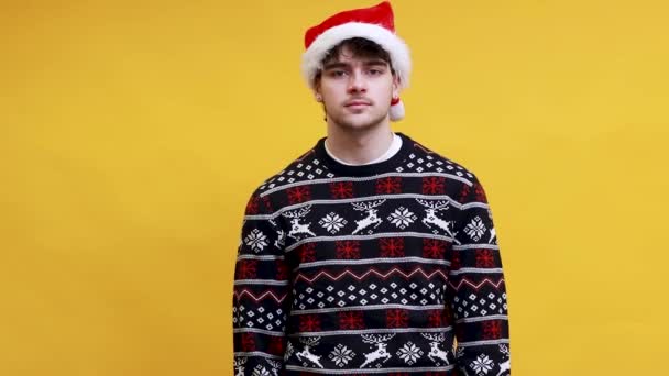 Kaukasischer junger Mann mit Weihnachtsmann-Hut und verständnislosem Gesichtsausdruck - Filmmaterial, Video