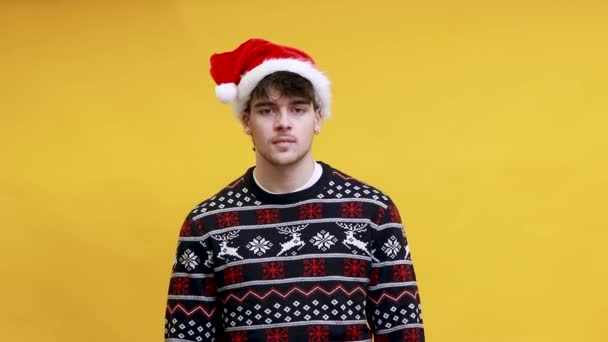 Noel Baba şapkalı genç, beyaz bir adam arka planda izole edilmiş kızgın ya da stresli. - Video, Çekim