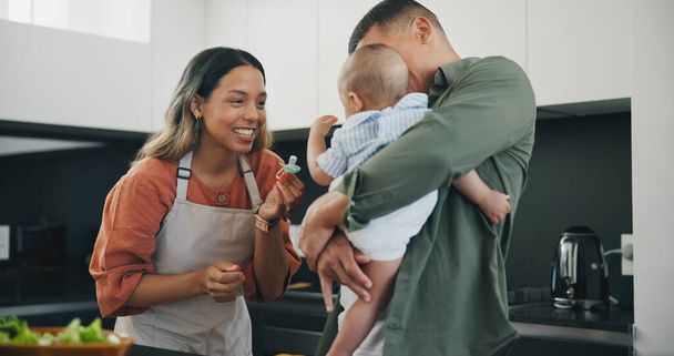 Family, smile and pacifier in kitchen, love and bonding or fun, relax and support or laughing on diet. Happy parents and baby, connect and humor or cooking, nutrition and healthy food or meal at home. - Photo, Image