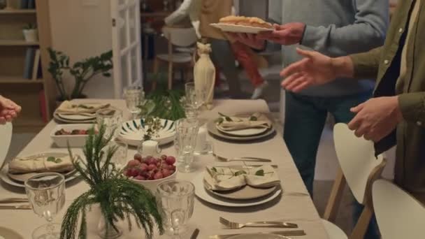 Leden van multi-generationele interculturele familie bereiden tafel voor feestelijk diner serveren het met cake en fruit - Video