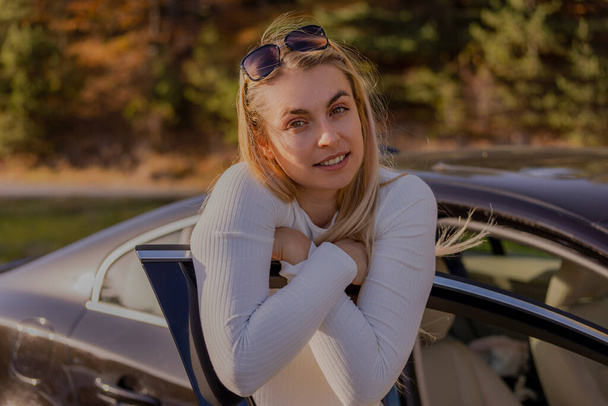 Beautiful Blonde Woman with Car and Sunglasses in Fall Setting - Travel Lifestyle - Foto, afbeelding