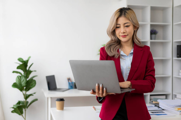 Junge Asiatin, die an ihrem Arbeitsplatz mit Laptop und Finanzdokumenten arbeitet, Freiberuflerin, Online-Marketing, Telemarketing-Konzept, E-Commerce - Foto, Bild