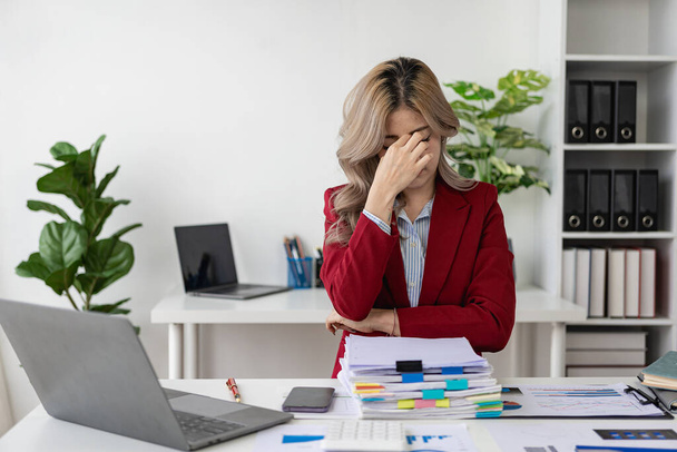 Młoda kobieta z bólem oka i stresem uczucie ciężkiej migreny pracująca na komputerze w biurze, kobieta zawroty głowy, podrażnienie, dotykanie świątyń, zmęczenie bólem głowy lub zmęczenie pracą. - Zdjęcie, obraz