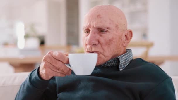 Homme âgé, café et pensée dans le salon, canapé et paisible pour se détendre, boire et seul. Retraite, vieillesse et personnes âgées dans la maison, boisson et matin pour expresso, thé et délicieux avec arôme. - Séquence, vidéo