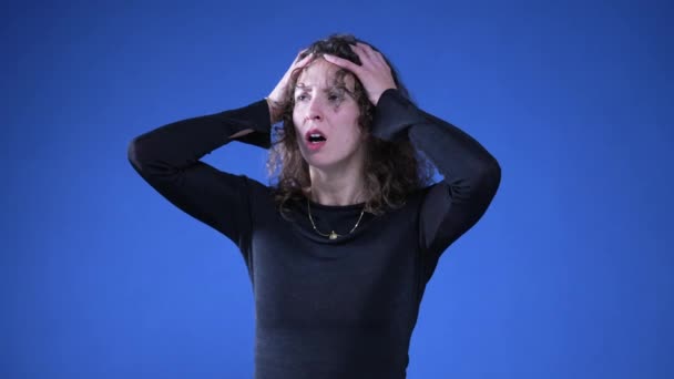 Angstige, angstige vrouw reageert met schok en wanhoop op nieuws door armen op het hoofd te leggen en mond te bedekken met ongeloof en verbazing - Video