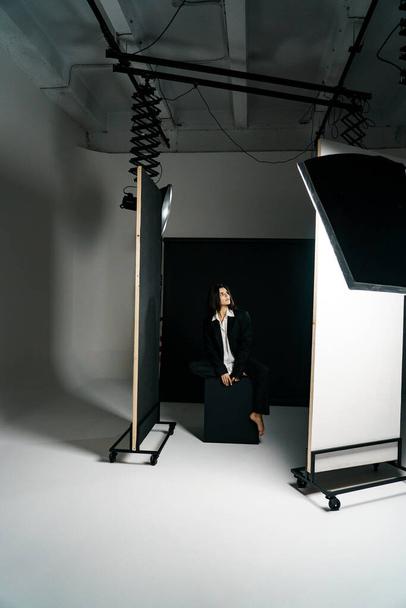 Profesyonel bir fotoğraf stüdyosunda siyah takım elbise ve beyaz gömlek içinde şık bir kız. Moda çekim konsepti - Fotoğraf, Görsel