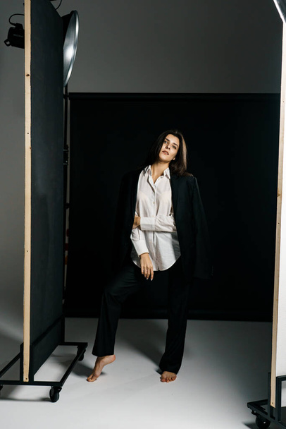 Profesyonel bir fotoğraf stüdyosunda siyah takım elbise ve beyaz gömlek içinde şık bir kız. Moda çekim konsepti - Fotoğraf, Görsel