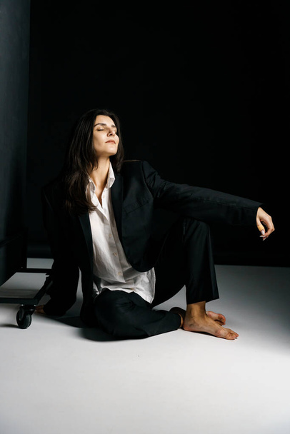 Menina elegante posando em um terno preto e camisa branca em um estúdio de fotografia profissional. Conceito de tiro moda - Foto, Imagem