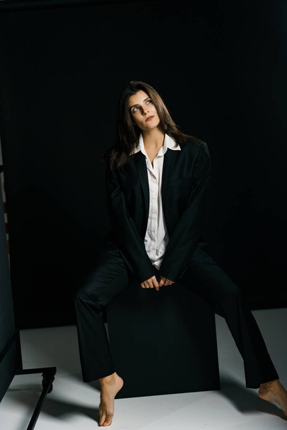 Stylowa dziewczyna pozowała w czarnym garniturze i białej koszuli w profesjonalnym studiu fotograficznym. Koncepcja fotografowania mody - Zdjęcie, obraz