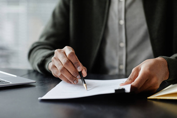 Gros plan d'un homme noir anonyme lisant un contrat en réunion et le signant avec un stylo, espace de copie - Photo, image