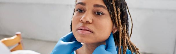 jeune femme afro-américaine regardant son médecin indien alors qu'il examine ses ganglions lymphatiques, bannière - Photo, image
