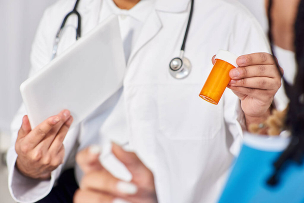 vista recortada del médico indio sosteniendo tableta y pastillas frente a su paciente afroamericano - Foto, imagen