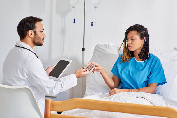 indian doctor holding tablet and giving pills to his african american female patient, healthcare - Photo, Image