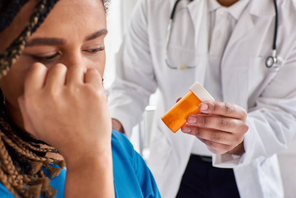 インドの医師の手の錠剤に焦点を当てる うつ病のアフリカ系アメリカ人の患者の隣 - 写真・画像