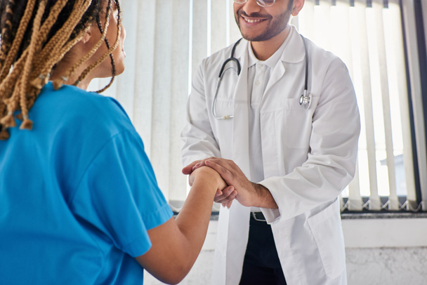 vista recortada del alegre médico indio estrechando la mano con su alegre paciente afroamericano - Foto, imagen