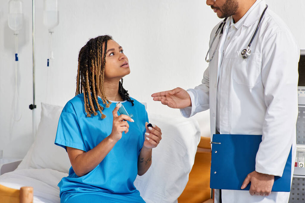 young indian doctor teaching his ill african american female patient how to use asthma inhaler - Photo, Image