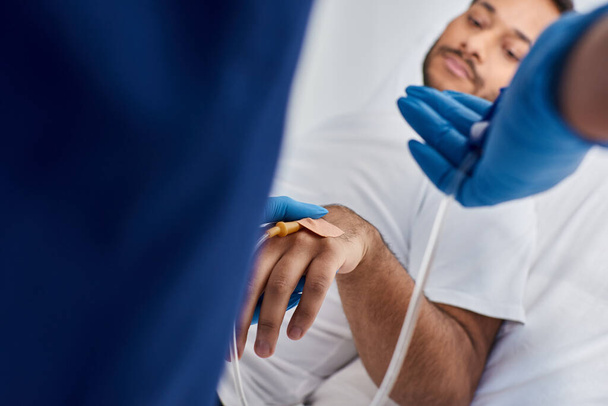 vista recortada de enfermera afroamericana insertando catéter en el brazo de su paciente indio, cuidado de la salud - Foto, Imagen
