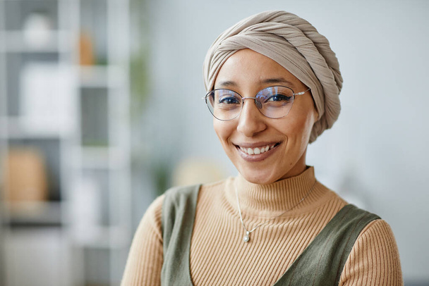 Minimális portré fiatal közel-keleti nőről, aki irodai környezetben mosolyog a kamerába és fejfedőt visel, másolja a helyet - Fotó, kép