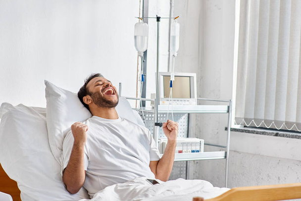 νεαρή ευτυχισμένη ινδική ασθενή επευφημίες και χειρονομίες ενεργά, ενώ στο κρεβάτι του νοσοκομείου, υγειονομική περίθαλψη - Φωτογραφία, εικόνα