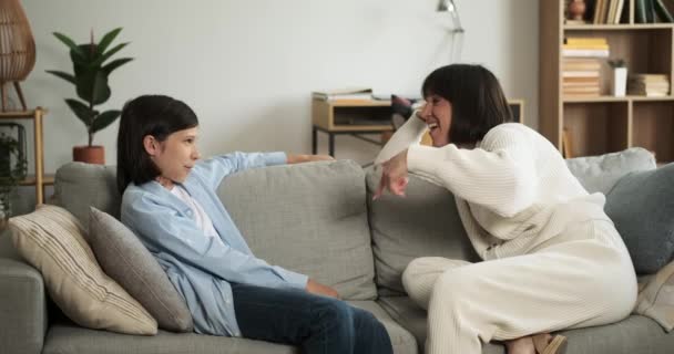 Mãe caucasiana alegre compartilha uma conversa agradável com o filho sorridente enquanto eles se sentam juntos no sofá. Sua interação irradia calor e afeto. - Filmagem, Vídeo
