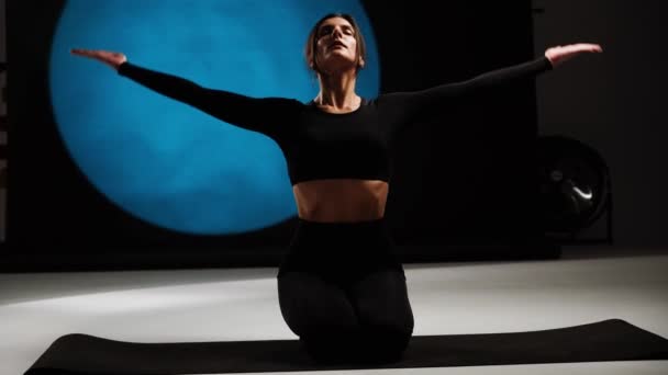 Een atletische vrouw die yoga doet in een fotostudio. Yoga en meditatie concept. 4k - Video