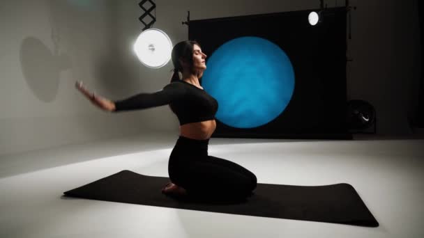 Atlétikai nő jógázik egy fotóstúdióban. Jóga és meditáció koncepció. 4k - Felvétel, videó