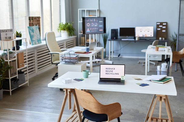 Рабочее место менеджера или главного исполнительного директора современной компании с ноутбуком и принадлежностями на фоне других столов - Фото, изображение