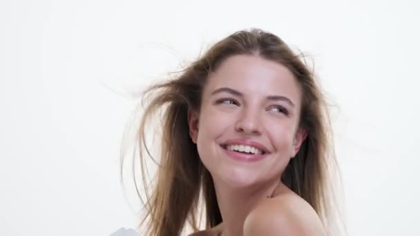 Woman gracefully dances while simultaneously blow-drying hair, showcasing a perfect blend of movement and style against a clean white backdrop. Her confident gestures exude energy and elegance. - Footage, Video