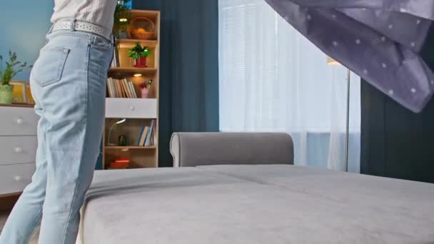 lição de casa, jovem mulher dobrando lençol no sofá antes de ir para a cama no quarto - Filmagem, Vídeo