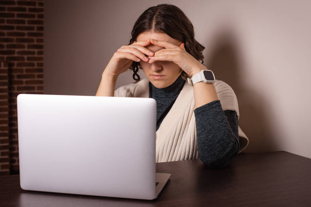 стресс женщина покрывает голову руками, думая о проблемах, работая в Интернете на дому - Фото, изображение
