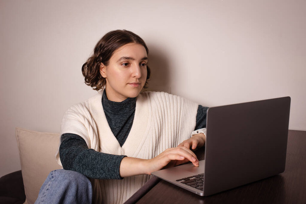 женщина работает дома на ноутбуке, минимализм на рабочем месте. тип фрилансера на клавиатуре для поиска информации - Фото, изображение