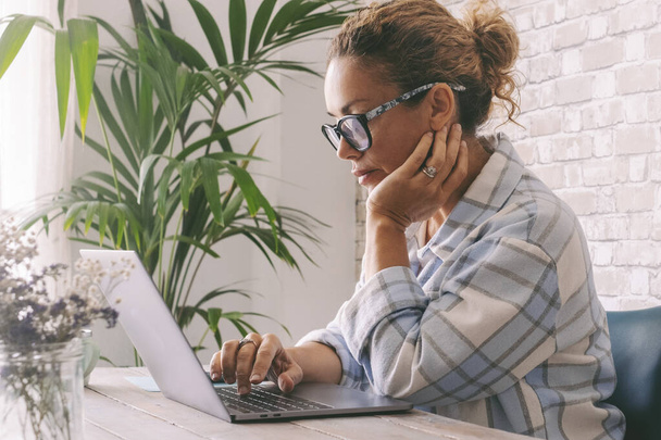 Skoncentrowana profesjonalna niezależna kobieta używająca laptopa w domu w biurze. Ludzie i cyfrowy smart pracujący online praca zawodowa. Kobieta pisać na komputerze z niepokojącym wyrażeniem - Zdjęcie, obraz
