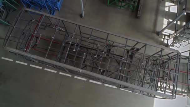 De framestructuur van de bus in de montagehal van de fabriek. Het concept van lasnaden bij de productie van personenvervoer. Luchtzicht. - Video