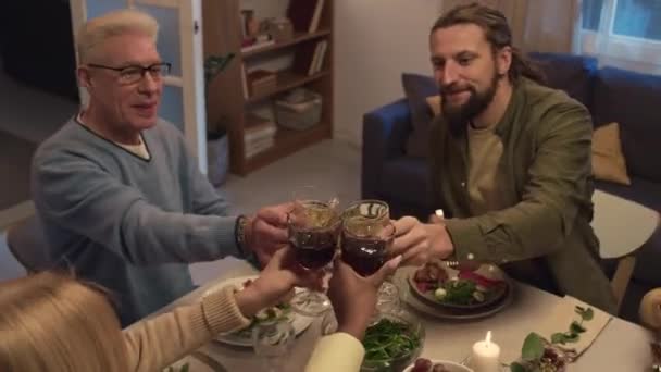 Vysoký úhel pohledu na rodinné cinkání sklenice s vínem při posezení u slavnostního stolu a oslavy akcí v útulném obývacím pokoji - Záběry, video