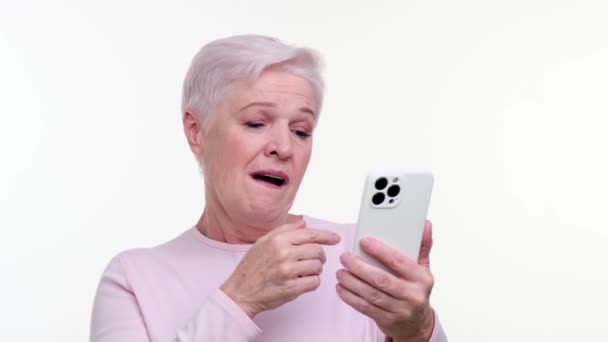 Ikävystynyt iäkäs nainen haukottelee käyttäessään puhelinta, silmät heijastavat hetkellistä mielenkiinnon menetystä. Hänen väsynyt ilmeensä vangitsee ohikiitävän tylsyyden tunteen, joka esittelee suhteellista kokemusta.. - Materiaali, video