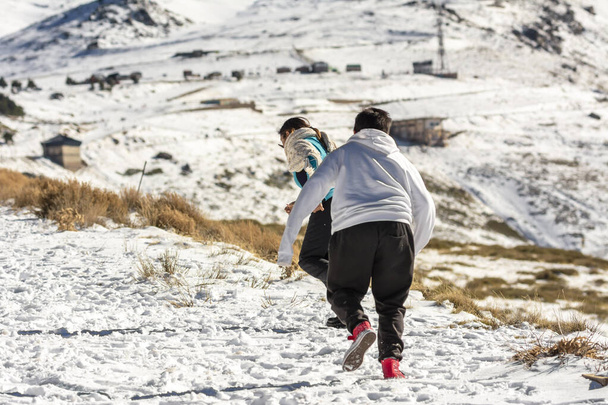 Latin mother and son running in the snow in Sierra Nevada Granada, Andalusia Spain - Photo, Image