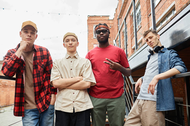 Různorodá skupina chlapů ve stylu ulice a při pohledu na kameru ve městě, mužský hip-hop tým - Fotografie, Obrázek