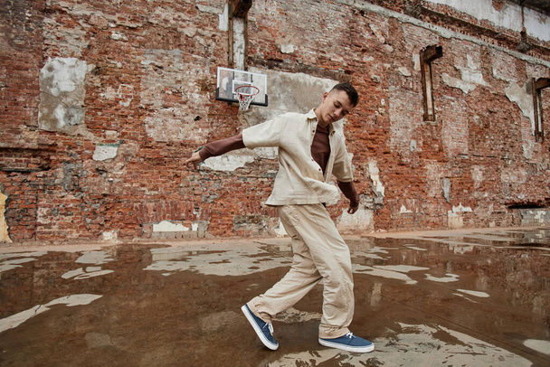 Freeze frame of male breakdancer performing against shabby brick wall outdoors, copy space - Photo, Image