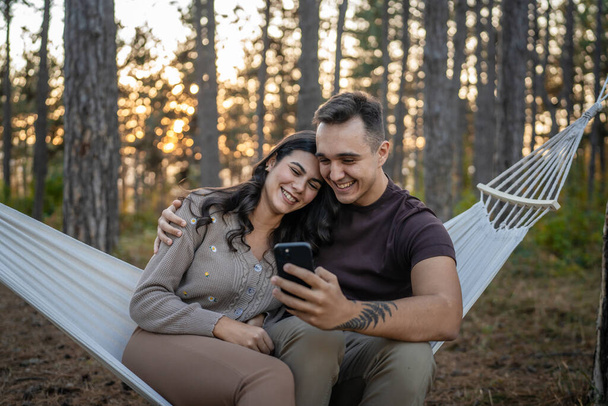Man and woman young adult couple in nature take self portrait photo selfie ugc use mobile phone smartphone or make a video call - Photo, Image