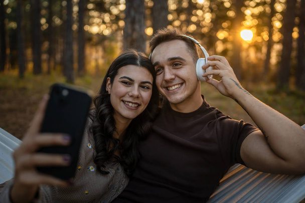 Мужчина и женщина молодая пара в природе сделать автопортрет фото ugc ugc использовать смартфон мобильного телефона или сделать видео-звонок - Фото, изображение