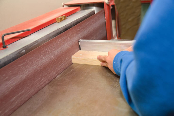 Carpintero arenas pieza de madera en una lijadora de cinturón taller de madera - Foto, Imagen