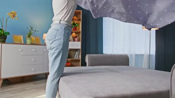 tarefas domésticas, jovem dona de casa dobrando na roupa de cama após o sono no quarto acolhedor - Filmagem, Vídeo