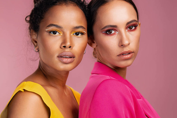 Γυναίκα λάμψη στούντιο αγώνα δέρμα κορίτσι αμερικανική δύο πολύχρωμα bodycare υγιή ελκυστική ομορφιά ευτυχισμένη αφρικανική πορτρέτο όμορφο πρόσωπο μοντέλο make-up μαζί μικτή κίτρινο - Φωτογραφία, εικόνα