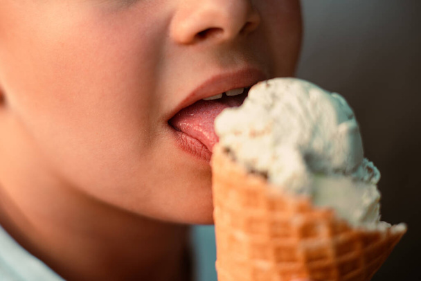 Vista de cerca de un niño comiendo helado en una taza de gofre. Macro. Vista detallada de una lengua en helado, hora de verano, infancia feliz. Foto de alta calidad - Foto, Imagen
