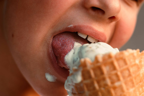 Waffle bardağında dondurma yiyen bir çocuğun yakın çekim görüntüsü. Makro. Dondurmadaki bir dilin detaylı görüntüsü, yaz zamanı, mutlu bir çocukluk. Yüksek kalite fotoğraf - Fotoğraf, Görsel